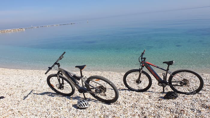 Foto di due e-bike sulla spiaggia a riva del mare